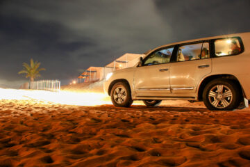 4x4 vehicle parked on sand dunes in a desert camp at night