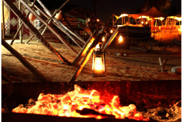 Lantern-lit desert campfire with rustic decor under the night sky.