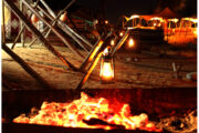 Traditional lanterns glowing beside a wooden frame in a desert camp at night