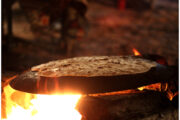 Traditional bread being cooked on an open flame in a desert setting