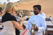 Guest receiving traditional Arabic coffee from a host in a desert camp