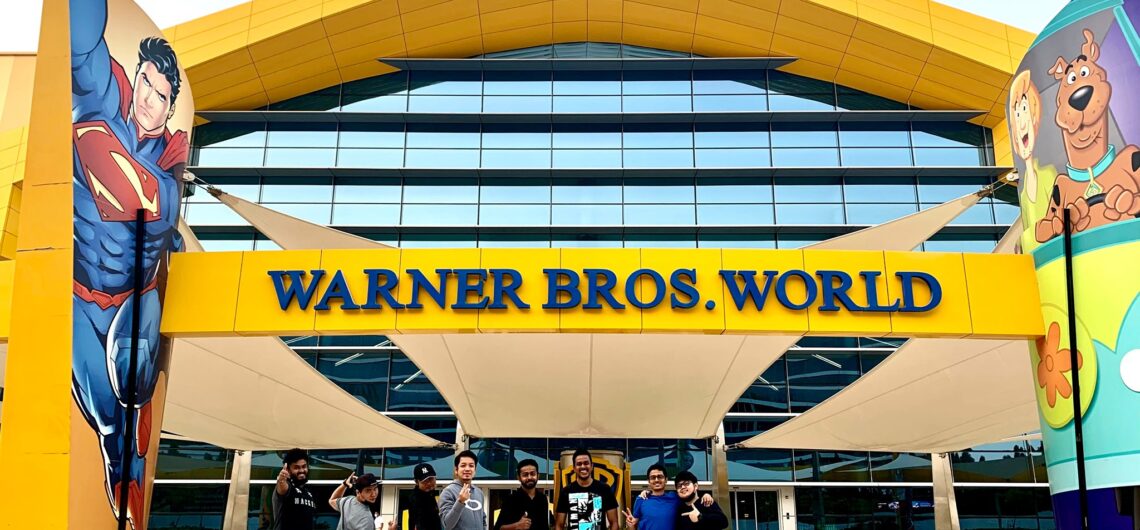 Visitors posing in front of the Warner Bros. World entrance with colorful cartoon-themed columns.