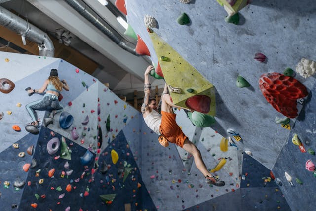 A man and a woman climbing a wall indoors