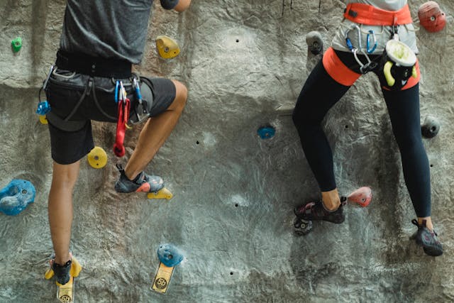 Two people in protective gear putting their feet on the handles on the wall