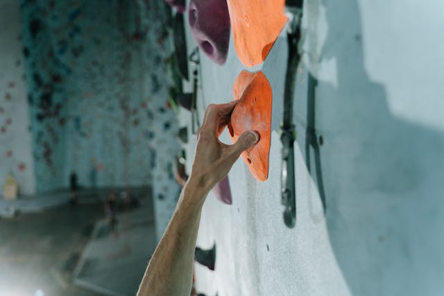 A person holding an orange handle on the wall