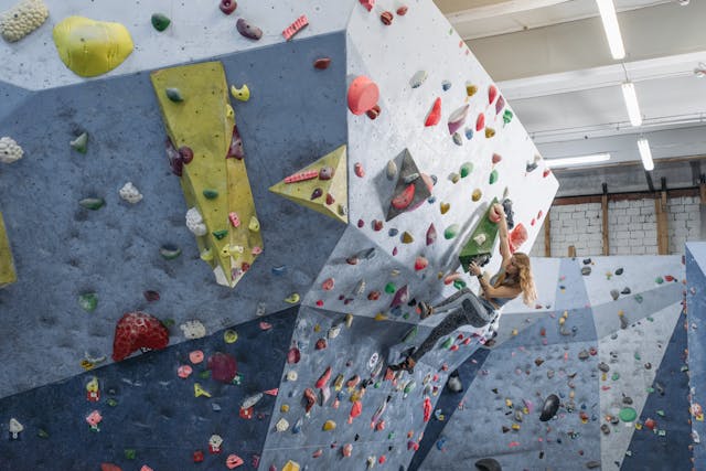 A woman going up a climbing wall