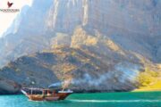 Traditional wooden boat cruising through a turquoise sea near rugged cliffs