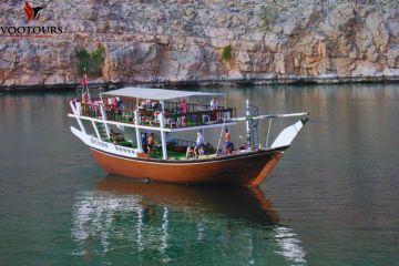 Traditional dhow boat anchored in serene waters with passengers enjoying the view