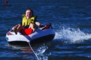 Person having fun on a donut ride over calm waters.