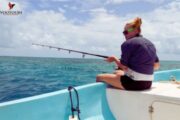 Woman fishing from a boat in clear turquoise waters