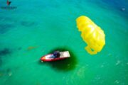 Aerial Parasailing Adventure - A top-down view of a parasail and boat in turquoise waters.