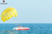 Yellow Parasail in the Sky - A vibrant yellow parasail attached to a boat over crystal-clear waters.