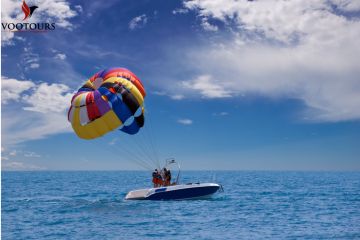 Multicolored parasail floating above a boat in the open ocean.