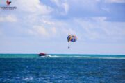 Parasailing adventure with a colorful parachute over turquoise sea.