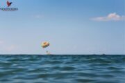 Distant parasailing activity over calm waters under a blue sky.