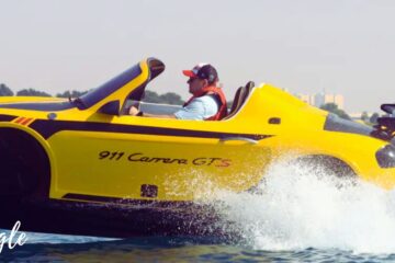 A sleek yellow Jet Car speeding across calm waters with a driver in focus.