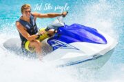 Man riding a blue jet ski through turquoise waters, creating an exhilarating splash in Ras Al Khaimah.