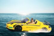 A close-up view of a yellow jet car, splashing through the waves with passengers.