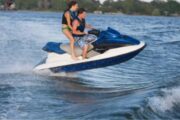 Couple riding a vibrant yellow jet ski on crystal-clear waters, embracing the thrill.