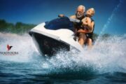 An elderly couple enjoying a thrilling jet ski ride together, surrounded by splashes.