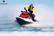 Jet ski rider in yellow racing through the waves on a vibrant red jet ski.