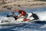 A man confidently maneuvering a red jet ski across the shimmering Arabian waters.