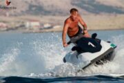 A solo rider maneuvering a black and white jet ski through the calm blue waters.