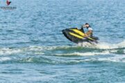 A man on a vibrant jet ski, racing across crystal-clear water with a stunning backdrop of Ras Al Khaimah