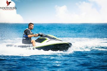 Close-up of a jet ski rider splashing through waves under the bright sun.