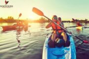 Group kayaking on calm waters during sunset.