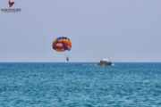 Parasailing experience with a vibrant parachute and a distant boat