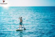 Solo Paddleboarder on Calm Blue Waters at Sunset