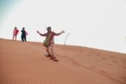 Adventurer enjoying sandboarding on the desert dunes