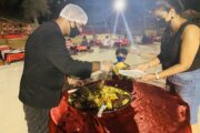 Chef serving BBQ dishes to a guest at a desert camp