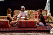 Guests being served traditional Arabic coffee in a cozy desert setup