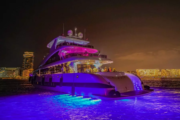 A luxury yacht glowing with purple lights on a night cruise in Dubai