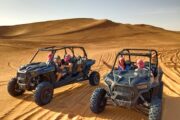 Two dune buggies with drivers resting in the desert.