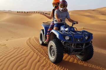 Two riders on a blue quad bike exploring the desert dunes