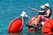 Senior couple riding a red water bike on the sea, enjoying a sunny day