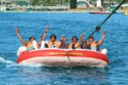 Group of four women enjoying a thrilling ride on an inflatable water tube on the open sea.