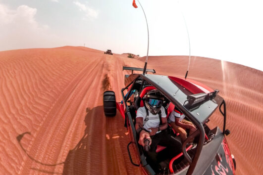 Aerial view of a driver riding a dune buggy across desert dunes.