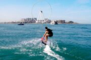 Person riding an Efoil board with Dubai skyline in the background.