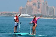 Couple riding electric stand-up paddle boards with Atlantis hotel in the background