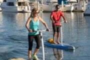 Man and woman exploring a marina on electric stand-up paddle boards