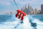 A Fly Fish inflatable soaring high over the ocean with Dubai skyline in the background.