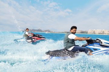 Three friends posing on jet skis with a stunning view of Dubai Marina's skyline