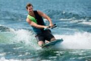 Enthusiastic rider enjoying a kneeboard ride on clear water.