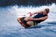 Man kneeboarding on a vibrant blue water surface.