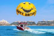 Yellow parasailing parachute with 'Happy Birthday' text over Dubai waters