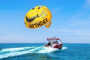 Birthday-themed parasailing with a smiley parachute and boat on the ocean